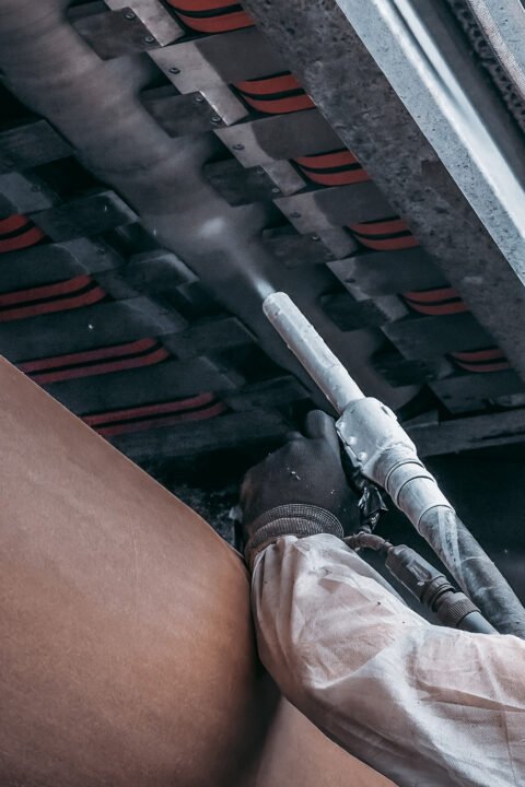 Trockeneisstrahlen Arbeiter reinigt industrielle Oberfläche mit Strahlpistole in Schutzkleidung